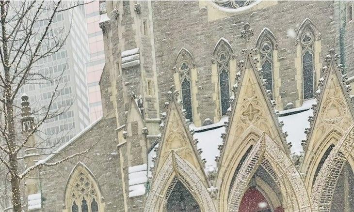 Une église de pierre et des immeubles sous la neige, dans un centre-ville canadien.
